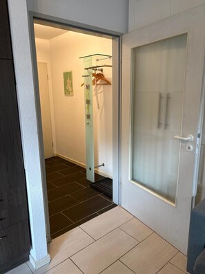 A hallway with a door leading to a room, a glass shower enclosure, and a coat rack with hangers. - Waldzeit Braunlage - WLAN - parking lot - terrace - at ground level (Braunlage)