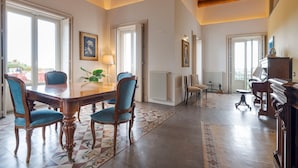 A dining area with a wooden table and blue upholstered chairs, a piano, and a radiator. - Villa with pool and breathtaking view - DiCasaInSicilia (Santa Venerina)