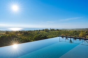 Una piscina infinita con vistas claras al océano y vegetación circundante.