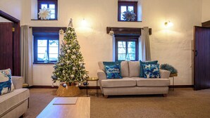 Una sala acogedora con un árbol de Navidad, un sofá con cojines decorativos y una mesa de centro de madera.
