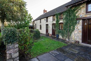 A stone building with ivy-covered walls, a small garden, and a stone pathway.