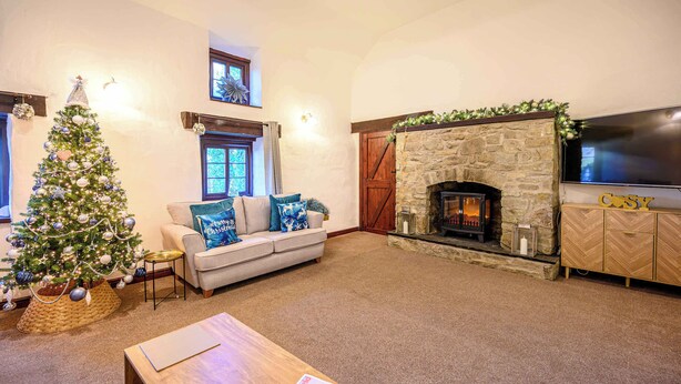 Una sala de estar acogedora con chimenea, un árbol de Navidad y un sofá cómodo.