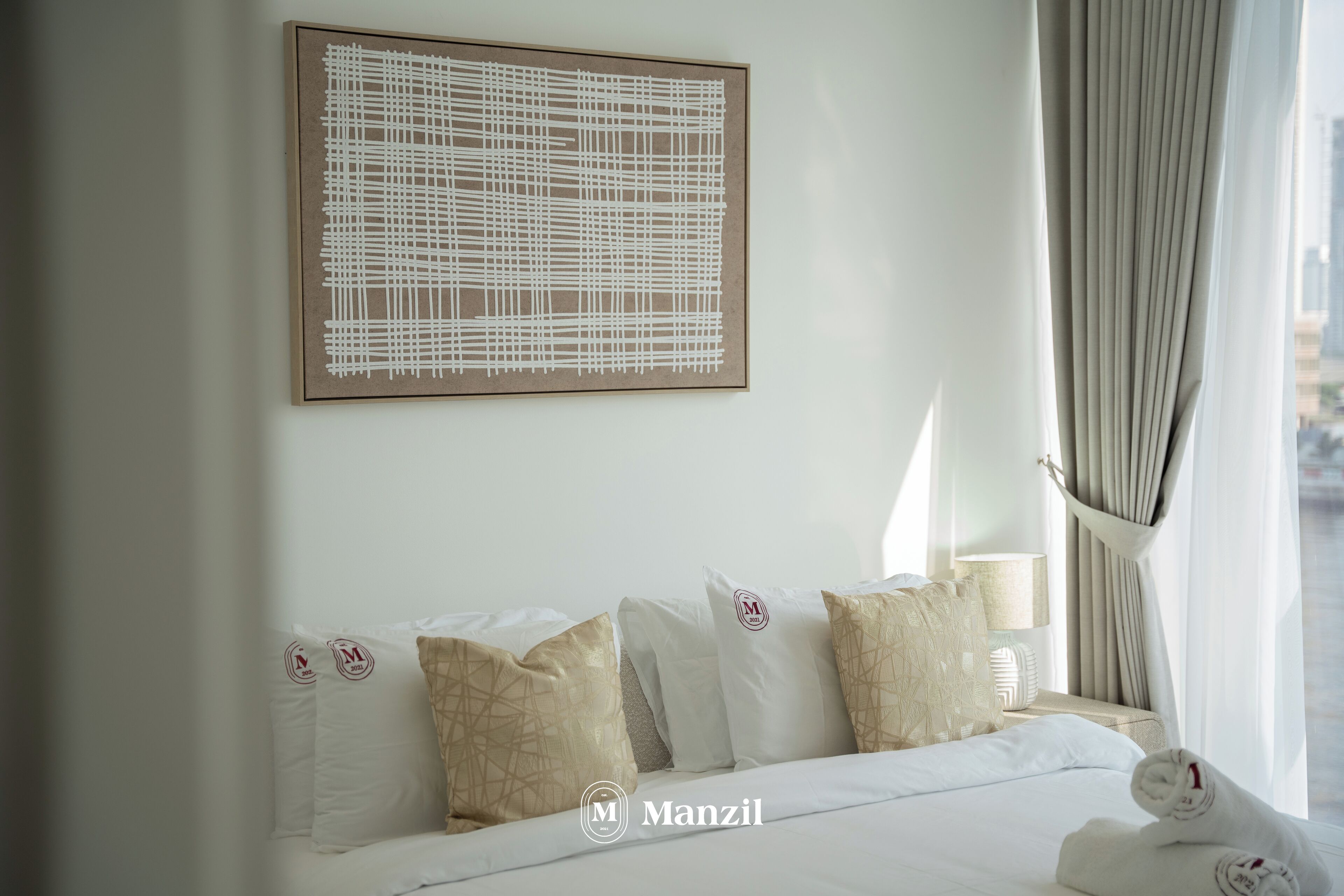A hotel room with a neatly made bed, a large abstract artwork on the wall, and a view of the city through the window.