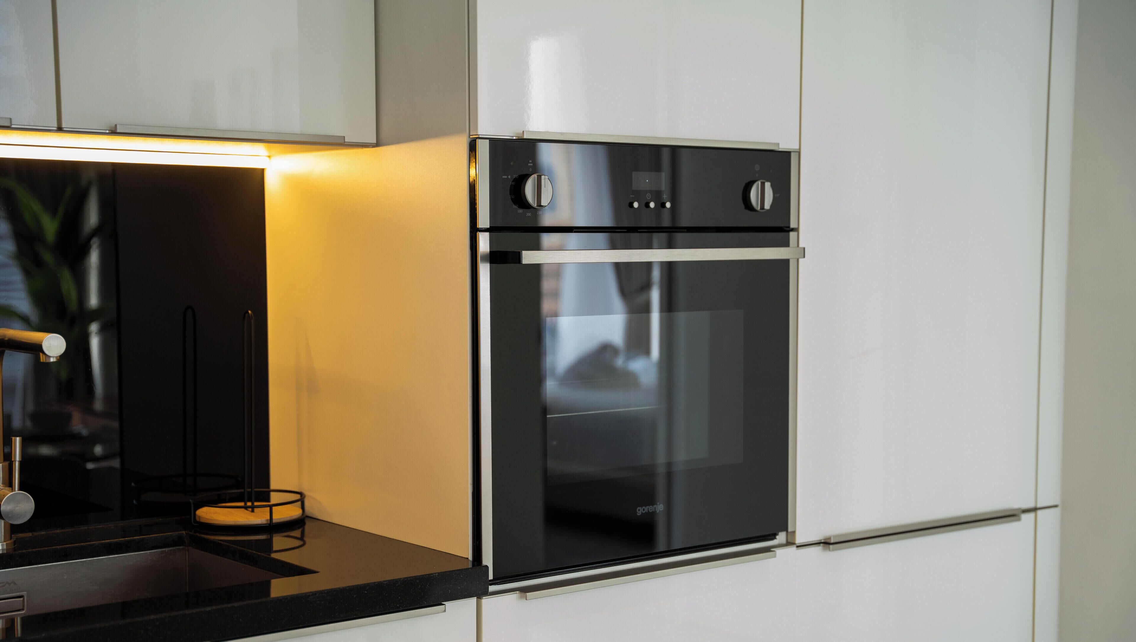 A modern kitchen with a built-in oven and a stainless steel range hood.