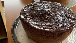 A cake on a glass plate on a wooden table. - Pousada Rota do Parque (Penha)