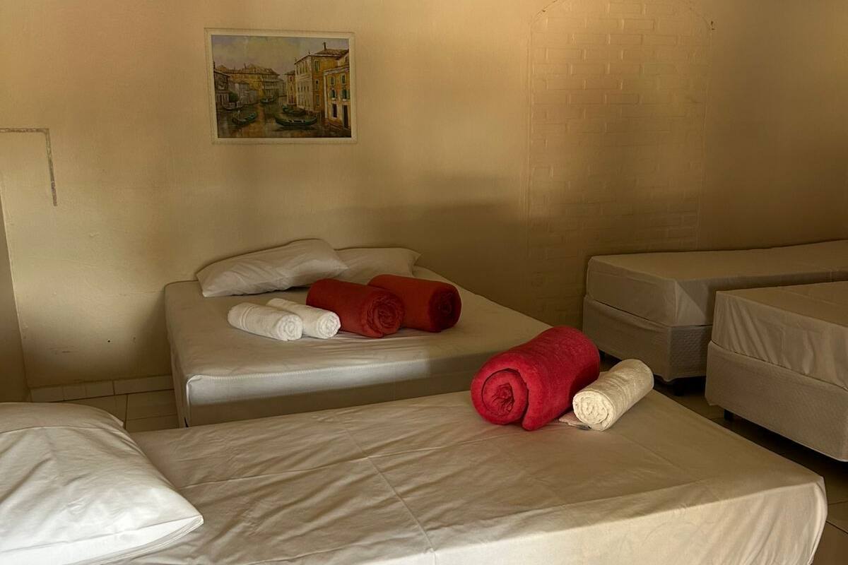 A hotel room with two single beds, a large bed, and a painting on the wall.