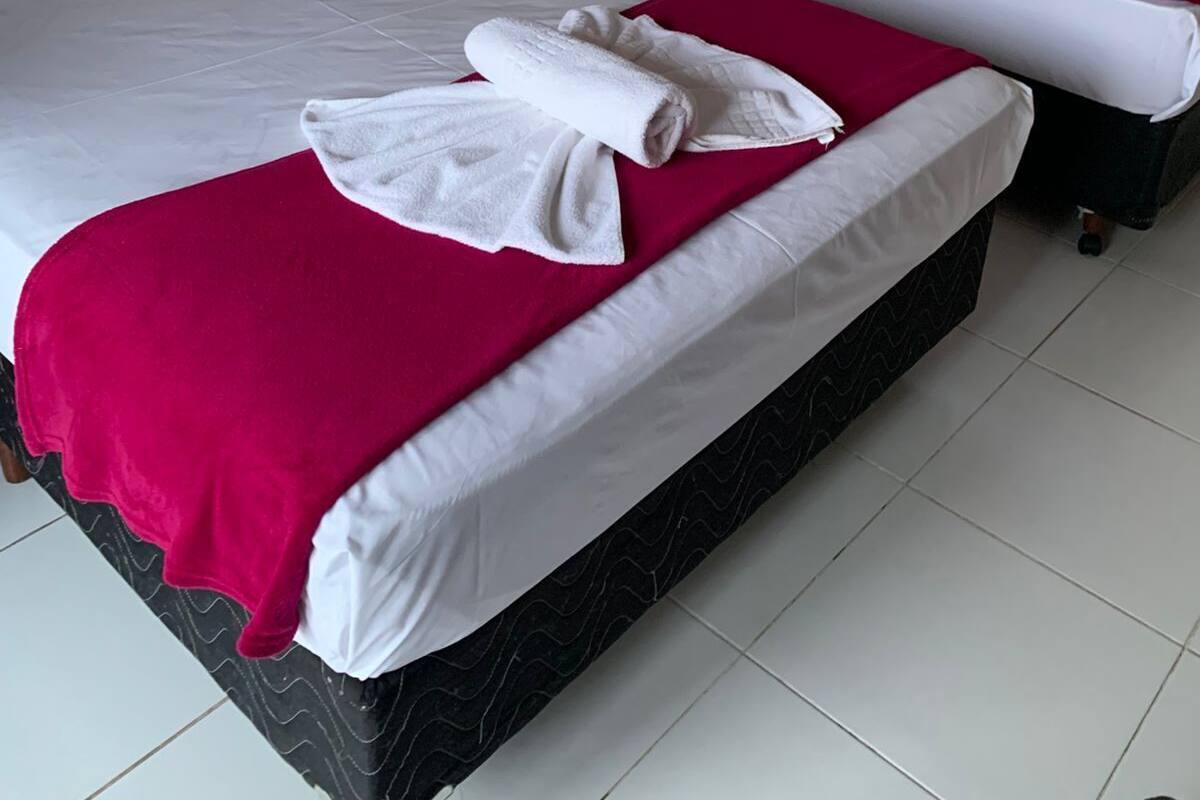 A hotel room with two beds, each with white bedding and red blankets.