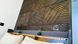 A hotel room with a bed, a headboard with a geometric pattern, a small plant, and a night light. - La Villa Bligny (Étretat)