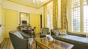 A room with a dining table, two armchairs, a sofa, and a glass coffee table. - La Villa Bligny (Étretat)