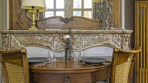 A wooden dining table with two chairs, a chandelier, and a mirror with decorative elements. - La Villa Bligny (Étretat)