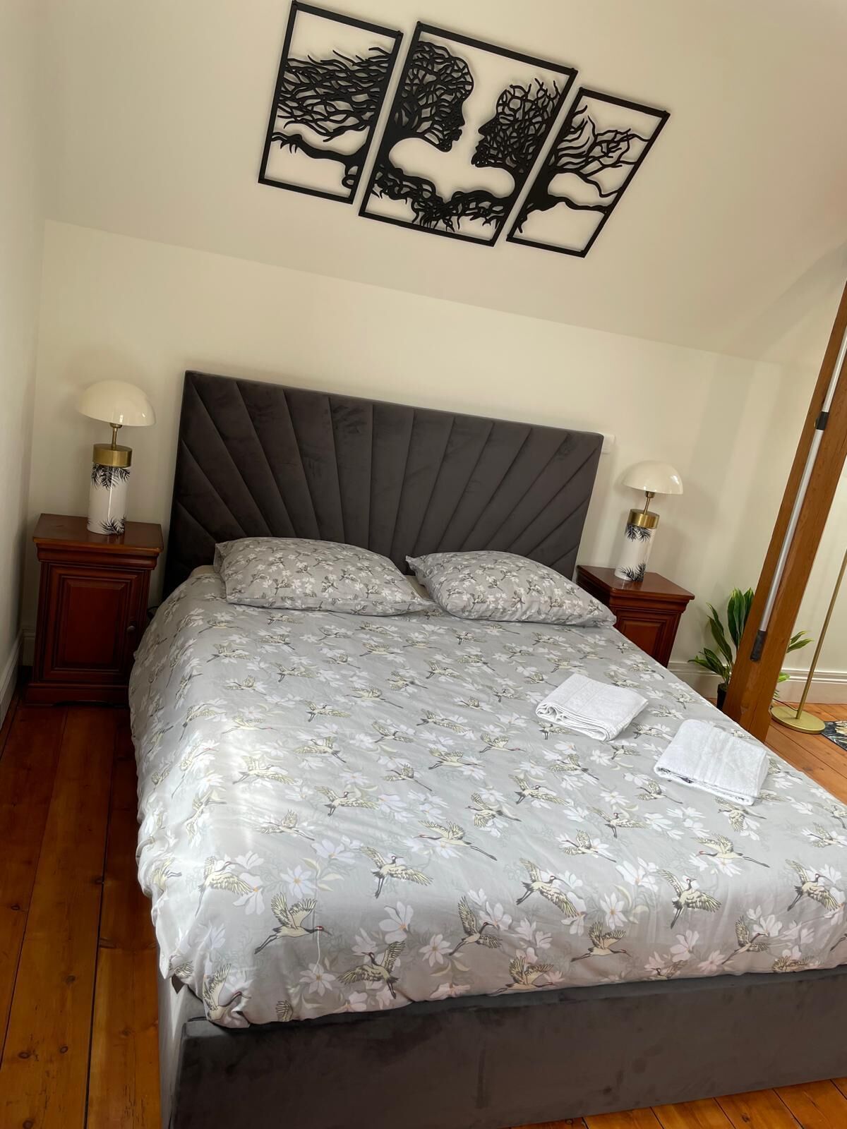 A neatly made bed with floral bedding, a dark headboard, and two bedside tables with lamps.