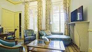 A traditional living room with a sofa, armchairs, a coffee table, and a television. - La Villa Bligny (Étretat)
