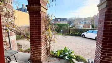 An outdoor patio area with brick arches, a metal table, and a car parked in the background.