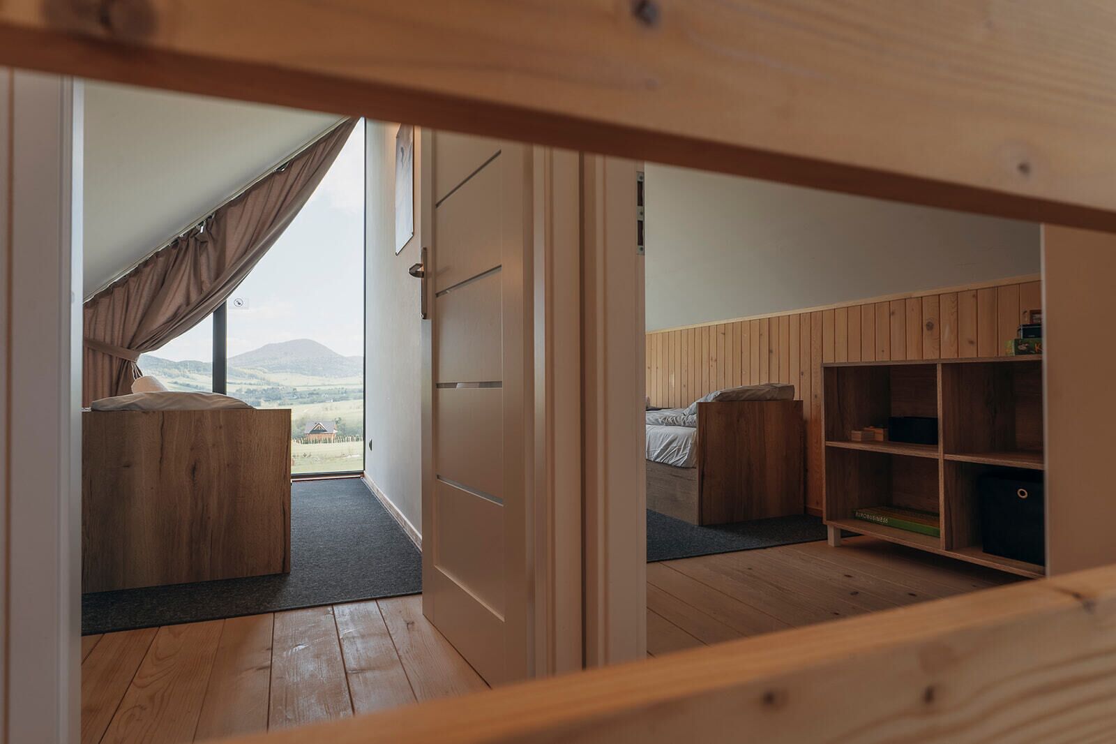 A bedroom with a bed, a wooden wardrobe, and a view of the outdoors.