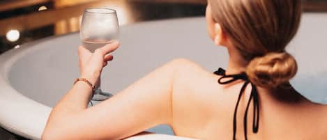 A person in a hot tub holding a glass.