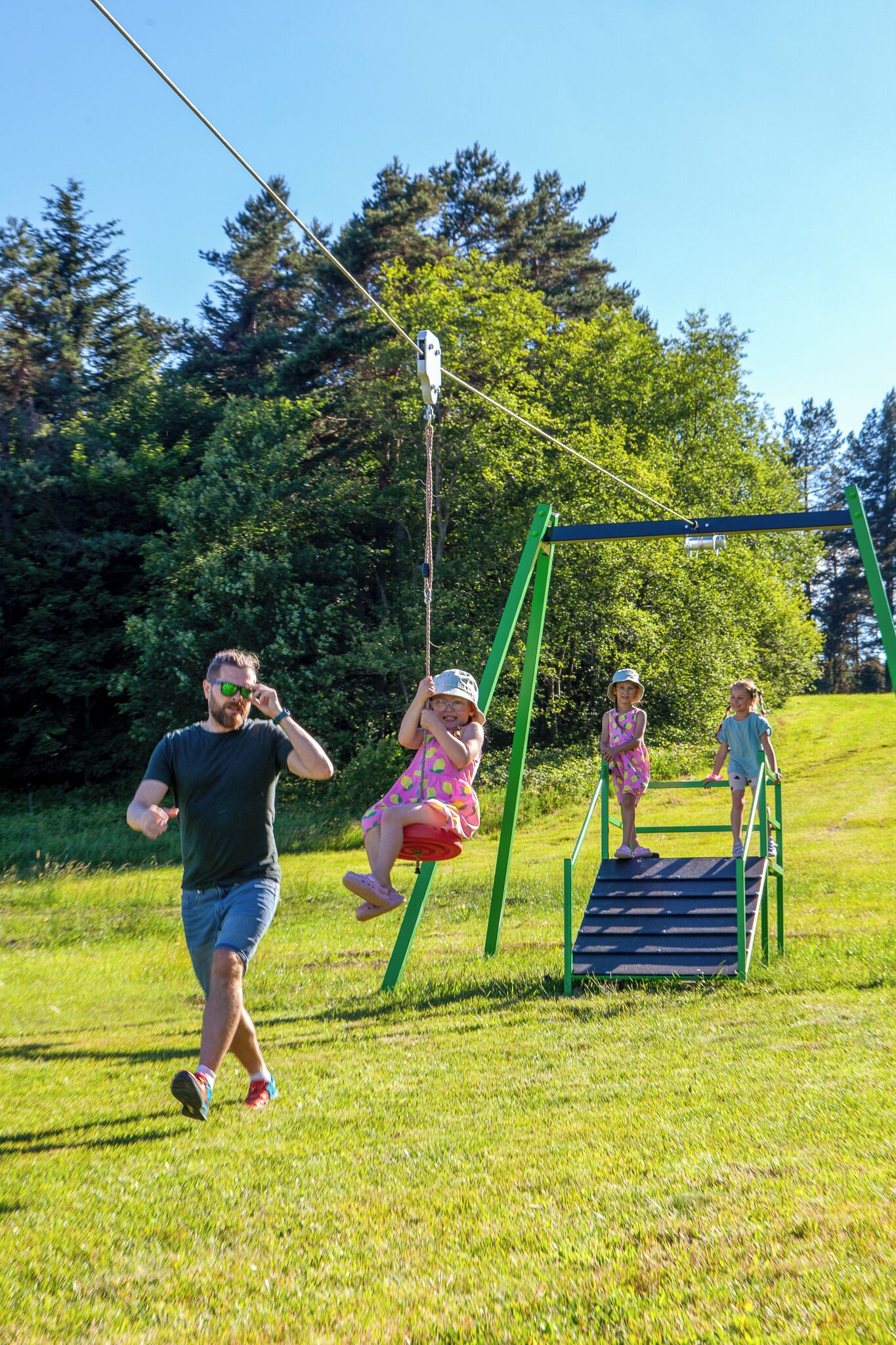 A swing set in a grassy park with trees in the background.