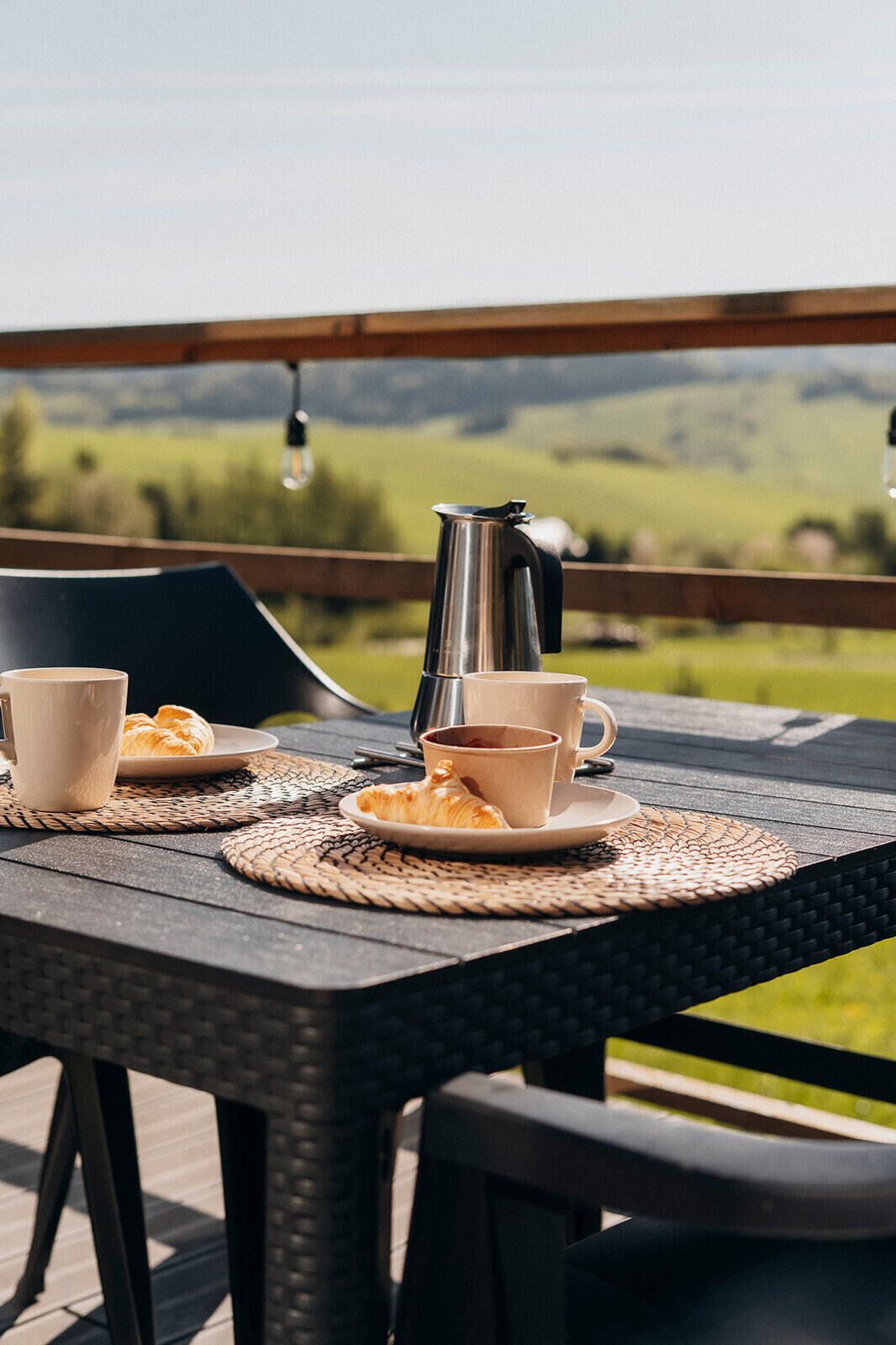 A table set outdoors with a view of a green landscape.