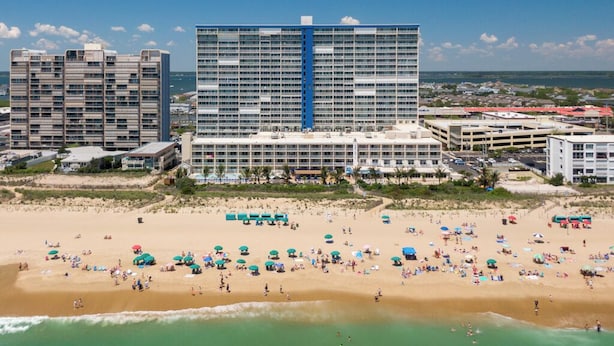 A beachfront hotel with multiple floors, a pool area, and beach umbrellas. - Two-bedroom oceanfront with indoor and outdoor pools! (Ocean City)