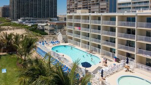 A hotel with a large pool area, multiple balconies, and a view of the surrounding buildings. - Two-bedroom oceanfront with indoor and outdoor pools! (Ocean City)