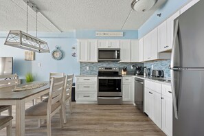 Eine moderne Küche mit weißen Schränken, einem Edelstahl-Kühlschrank und einer blauen Küchenrückwand.