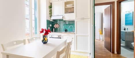 Una cocina moderna con armarios blancos, una mesa de comedor con sillas y un florero con flores.