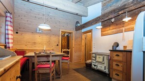 A wooden interior with a dining table, chairs, and a kitchen area with vintage appliances. - Chalet Hühnerstall am Soderhof - peace and quiet and private SPA in the Salzburg mountains (Unken)