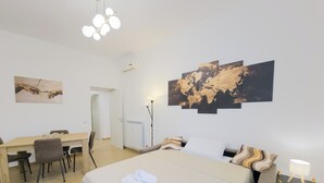 A hotel room with a bed, a desk, a chair, a map artwork, and a lamp. - Testaccio Patty Flat (Rome)