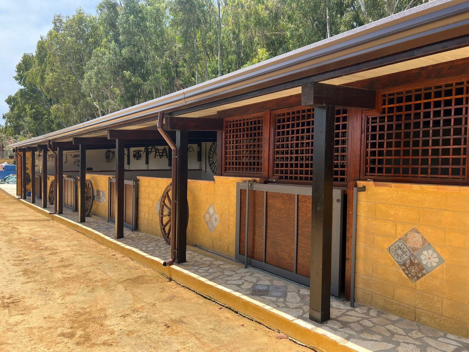 A building with a covered walkway, wooden columns, and a tiled wall.