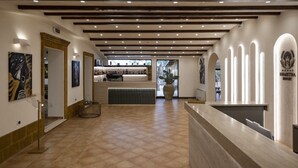 A hotel lobby with a reception desk, a bar area, and a large potted plant. - Villa Demetra Resort (Agrigento)