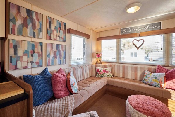 A cozy living room with a sectional sofa, a wooden coffee table, and abstract wall art.