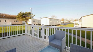 A deck with wicker furniture and a clear view of mobile homes in the background. - Host & Stay | Cosy Cove (Cresswell)