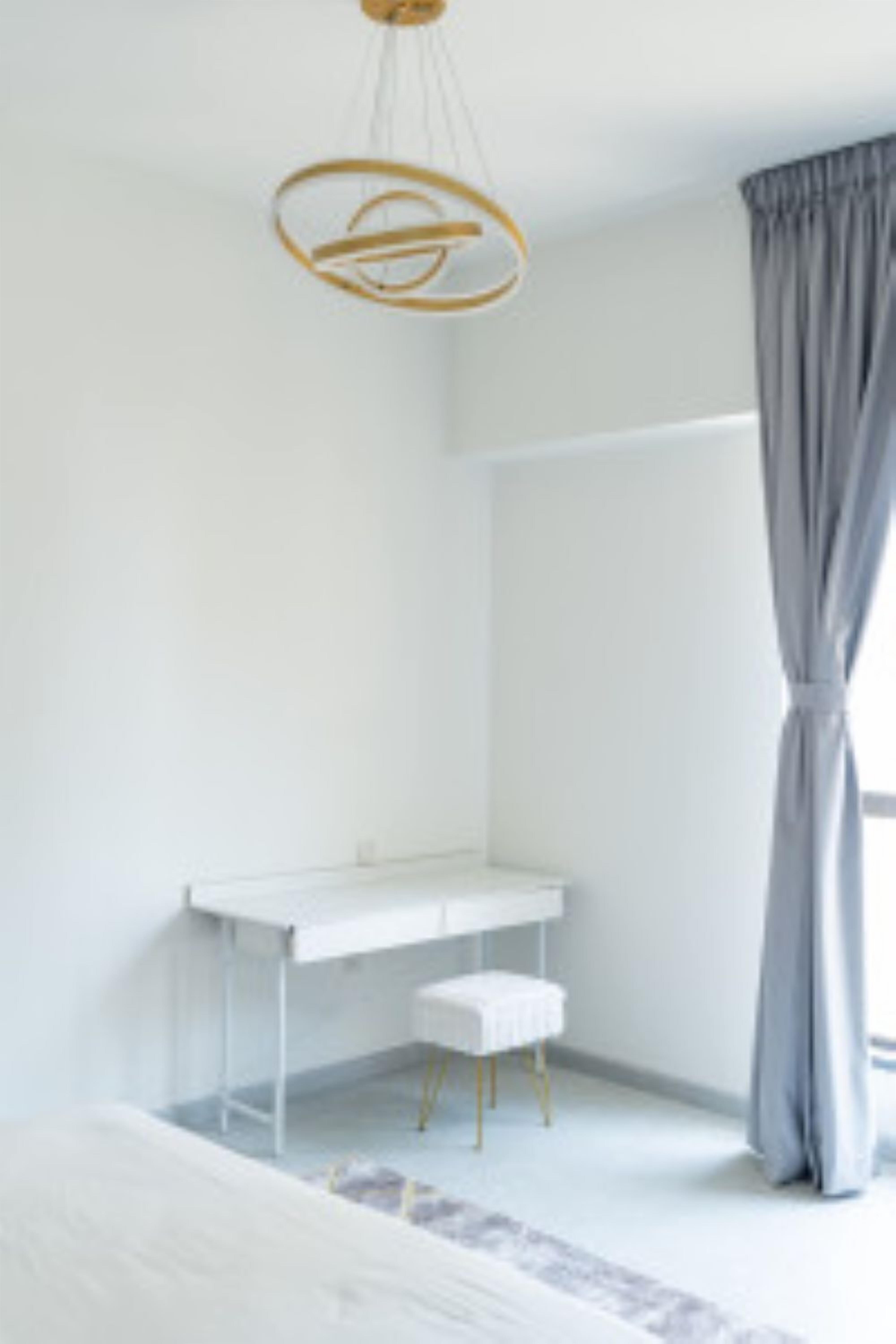 A modern bedroom with a white bed, a desk, and a chair.