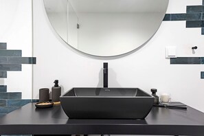 A modern bathroom with a black sink, a round mirror, and a black countertop. - Regras Apartments & Garden A11 by Benefit Collection (Porto)