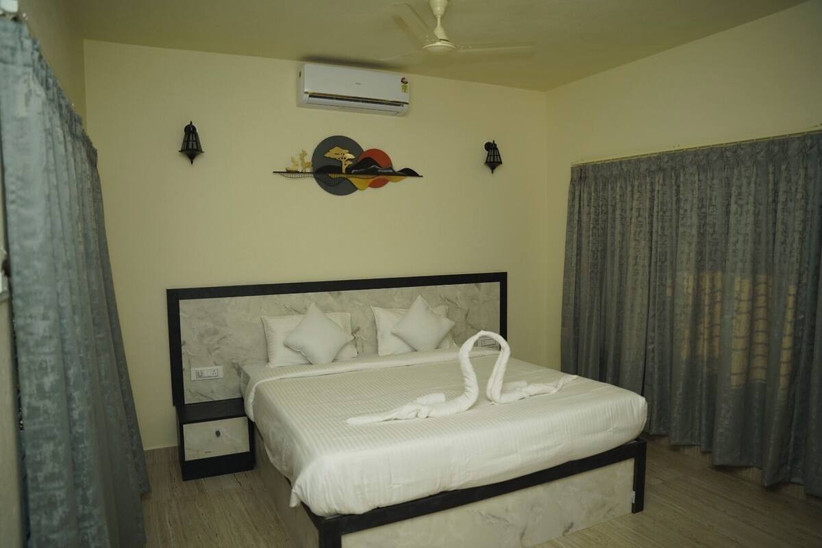 Quarto de hotel com cama, mesa de cabeceira, ar condicionado e uma obra de arte na parede.