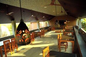 A spacious restaurant with high ceilings, wooden furniture, and pendant lighting. - Tungabhadra resort hampi (Hospet)