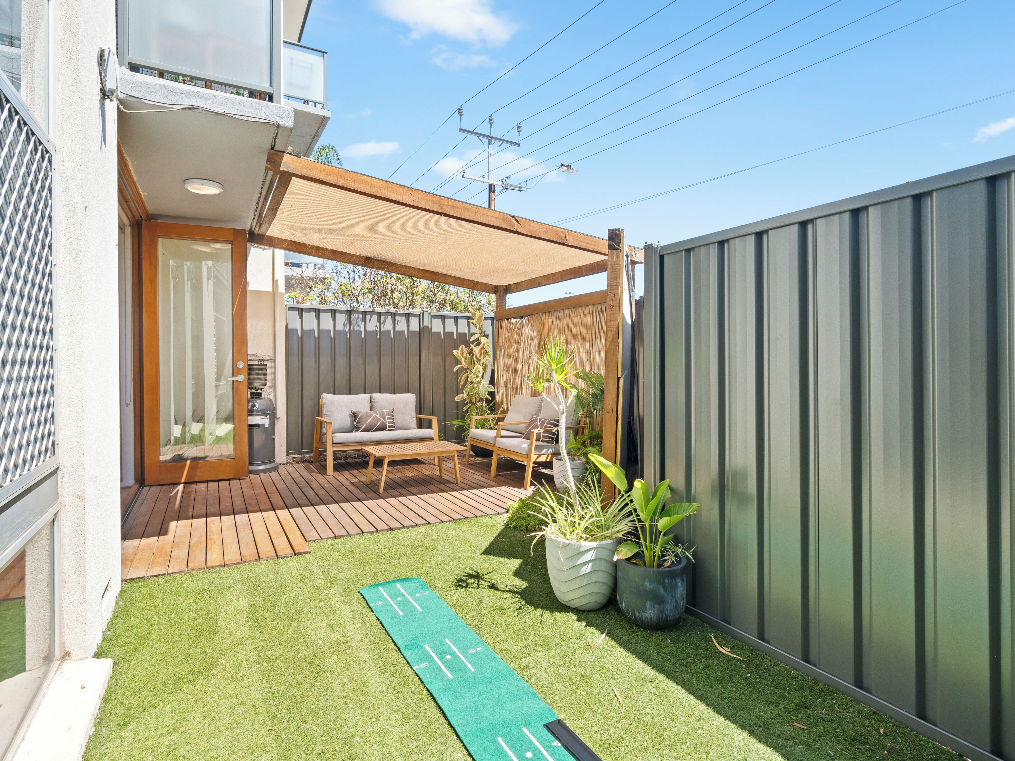 A patio with a wooden deck, a barbecue grill, and outdoor furniture.
