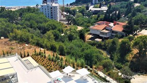 A hotel with a rooftop pool, surrounded by greenery and a view of the sea. - Status apartments 173 (Becici)