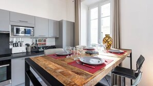 Une cuisine moderne dotée d’un îlot central en bois, d’appareils électroménagers en acier inoxydable et d’un coin repas avec une table dressée pour quatre personnes.