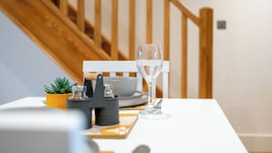 Une table à manger avec un verre d’eau, un bol et une petite plante en pot.