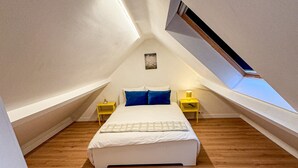 A bedroom with a sloped ceiling, a bed, two bedside tables, and a skylight. - Modern 1BR 1LR Apartment Walk To Rabot (Ghent)