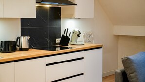 A modern kitchen with a black marble backsplash, white cabinets, and a wooden countertop. - Modern 1BR 1LR Apartment Walk To Rabot (Ghent)