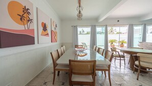 Un comedor con una mesa de vidrio, sillas de madera y obras de arte en las paredes.