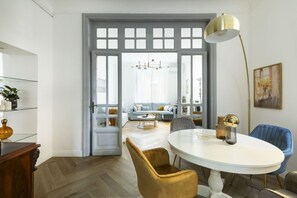 A dining area with a white table, gold chairs, and a gold pendant lamp. - Belle epoque house of mirror (Roma (RM))