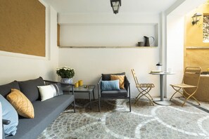 Een gezellige zithoek met een bank, twee stoelen, een klein tafeltje en een plant in pot.