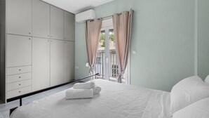 A bedroom with a bed, a wardrobe, and a balcony with curtains. - Litsa s Maisonette Near Sea - City Center (Chania)