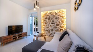 Un salon moderne avec un mur d’accent en pierre, un téléviseur à écran plat, un meuble de rangement en bois et un canapé confortable.