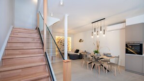 Une cuisine moderne dotée d’un four encastré et d’un coin repas avec une table et des chaises en bois.