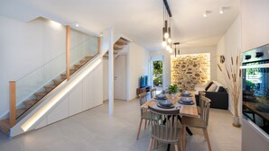 Un intérieur moderne comprenant un escalier, un coin repas et une cuisine.
