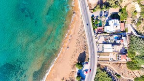 Une vue aérienne d’une zone côtière avec une plage, une route et des bâtiments.