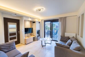Una sala moderna con un sofá, un televisor, una mesita y un ventanal corredera que da a un espacio exterior.